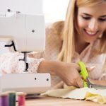 Smiling female designer cutting cloth in workshop